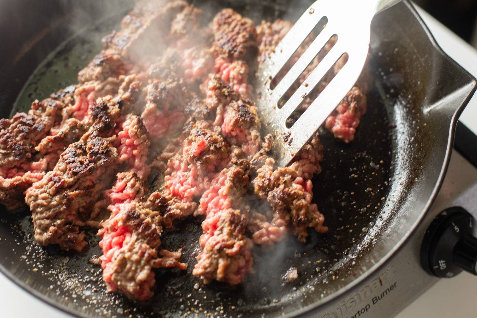 Browning ground beef in a cast iron skillet.