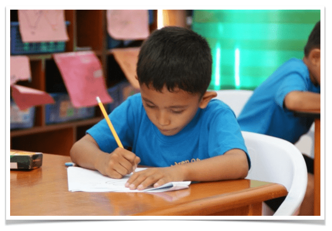 Young boy writing on paper.