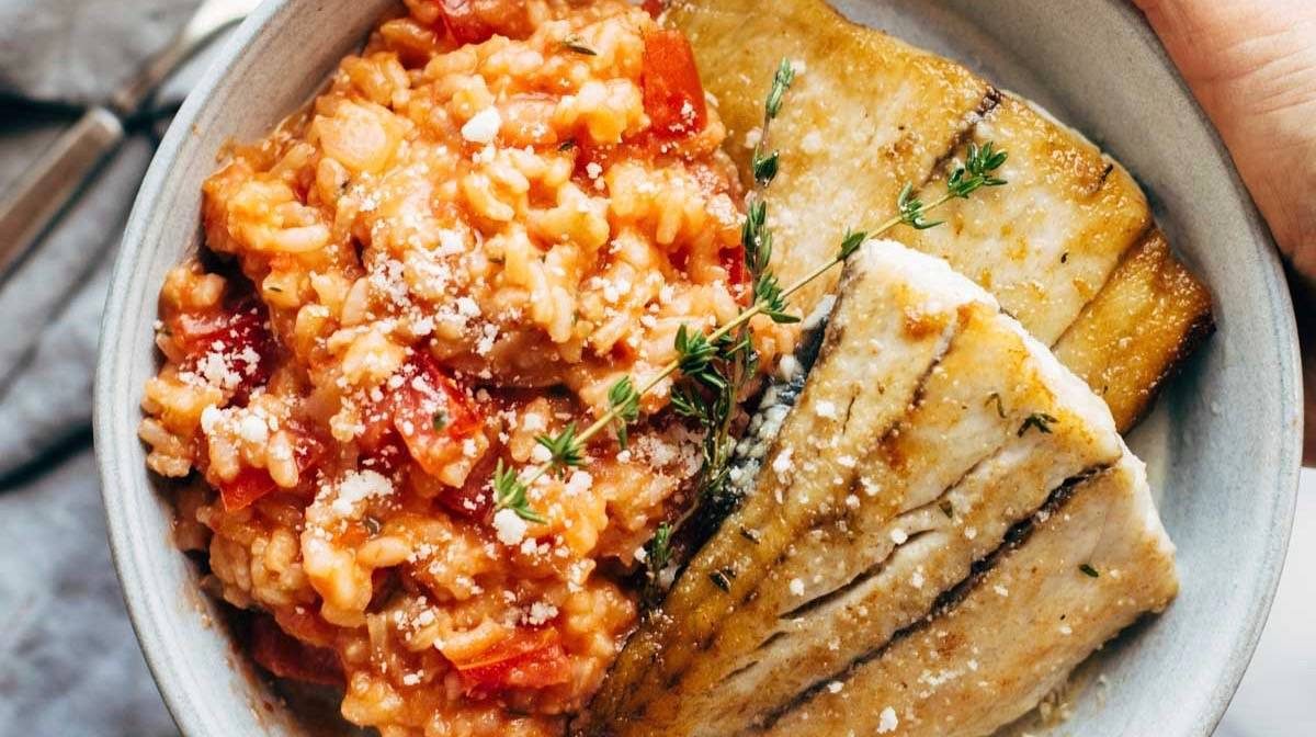 Barrumundi fish with tomato risotto on a plate.