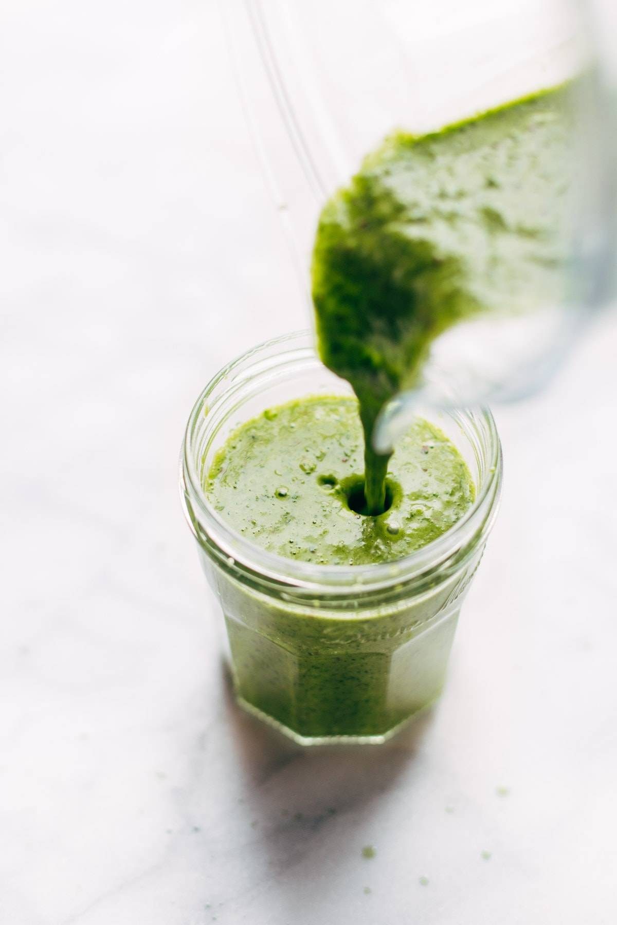 Pouring Cilantro Vinaigrette from a blender into a jar.